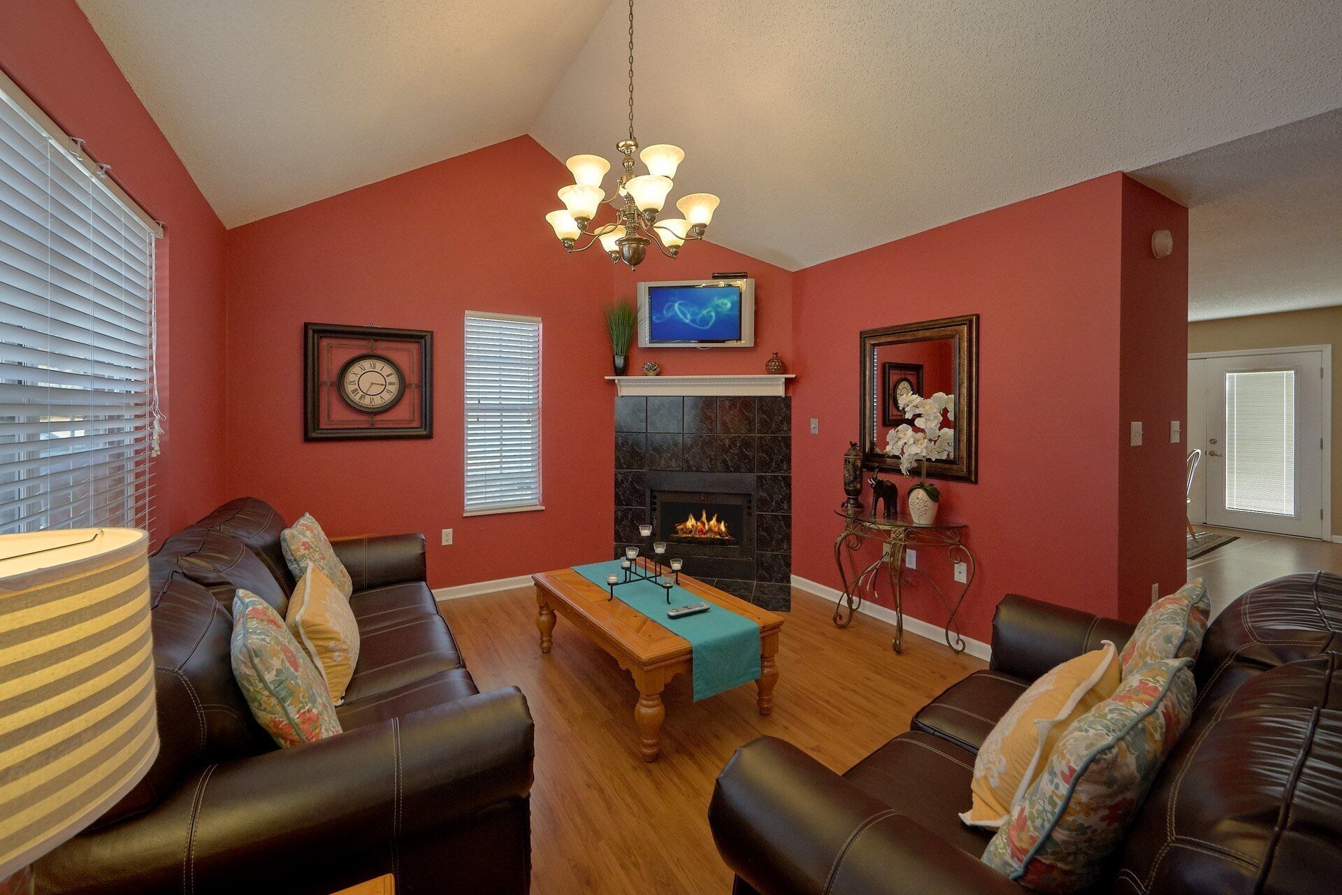 A living room with a fireplace, leather sofas, a coffee table, and a chandelier.