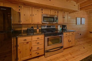 A wooden-paneled kitchen with a refrigerator, microwave, stove, and coffee maker.