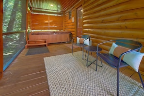 A wooden cabin interior with a hot tub, a bench, and a chair.