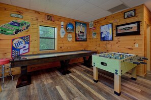 A room with wooden walls, a foosball table, a pool table, and various posters. - One More Night | Smoky Mtn Views, Hot Tub, Near Dollywood, Game Room + Free Attraction Tickets (Pigeon Forge)