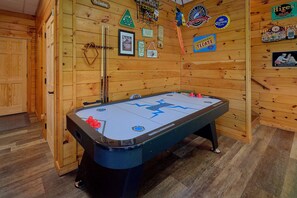 A pool table in a room with wooden walls, various signs, and a door. - One More Night | Smoky Mtn Views, Hot Tub, Near Dollywood, Game Room + Free Attraction Tickets (Pigeon Forge)