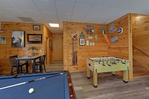 A room with a pool table, a foosball table, and a billiards table. There are wooden walls with various decorations and signs. - One More Night | Smoky Mtn Views, Hot Tub, Near Dollywood, Game Room + Free Attraction Tickets (Pigeon Forge)