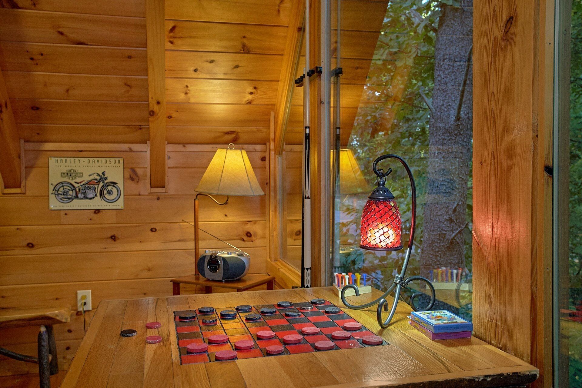 Un intérieur en bois avec une table préparée pour une partie, une lampe et une enseigne Harley-Davidson.