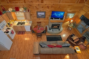 A cozy cabin interior with a dining area, kitchen, living room, and fireplace. - Our Happy Place | Hot Tub, Near Dollywood, Game Room, Fireplace + Free Attraction Tickets (Pigeon Forge)