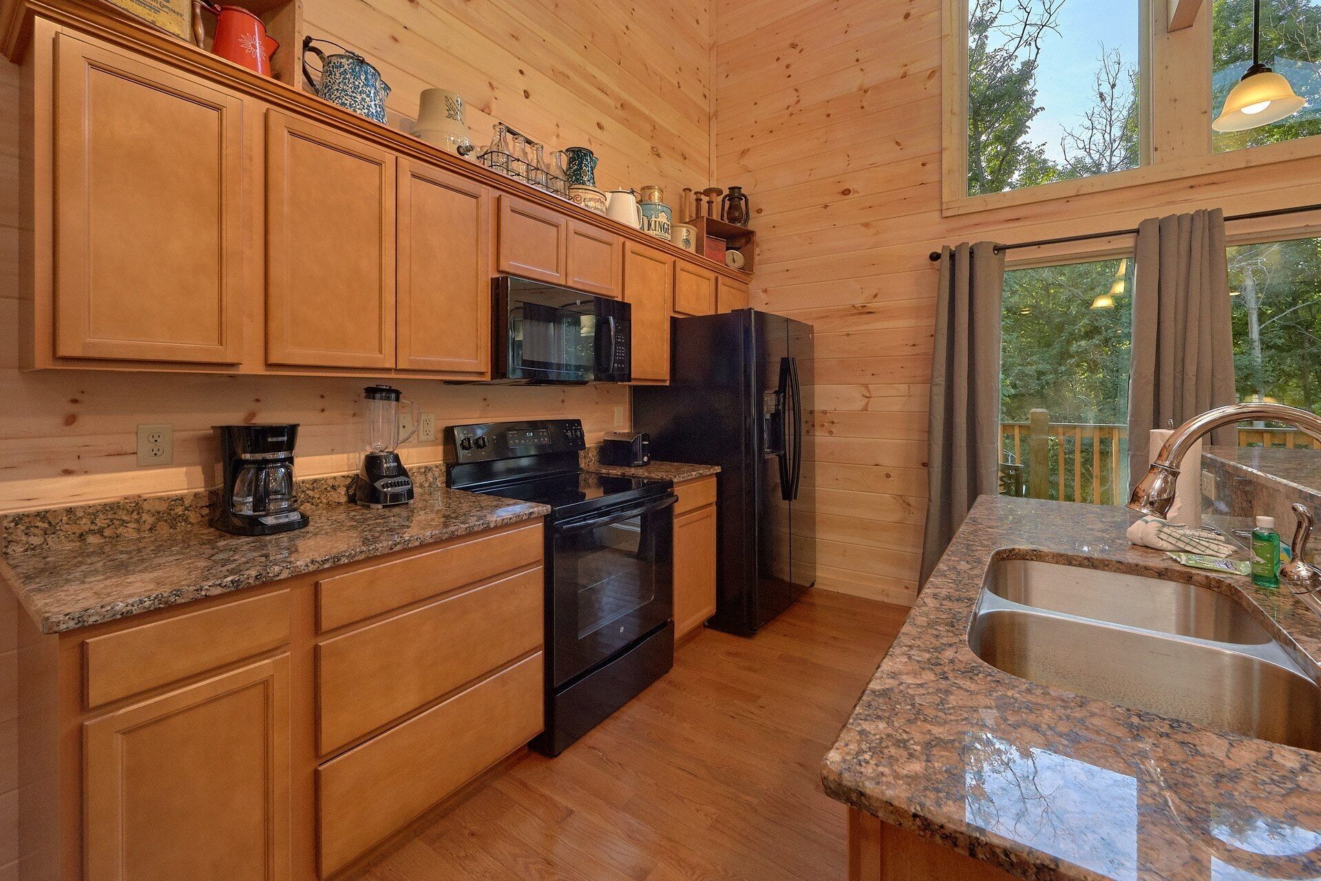 Una cocina con armarios de madera, microondas, refrigerador, estufa y encimera de granito.