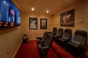 A movie theater with wooden walls, a red carpet, and posters for 'Jaws' and 'Ghost'. - Pool N Around | Indoor Pool, Hot Tub, Near Dollywood, Game Room, Fireplace + Free Attraction Tickets (Pigeon Forge)
