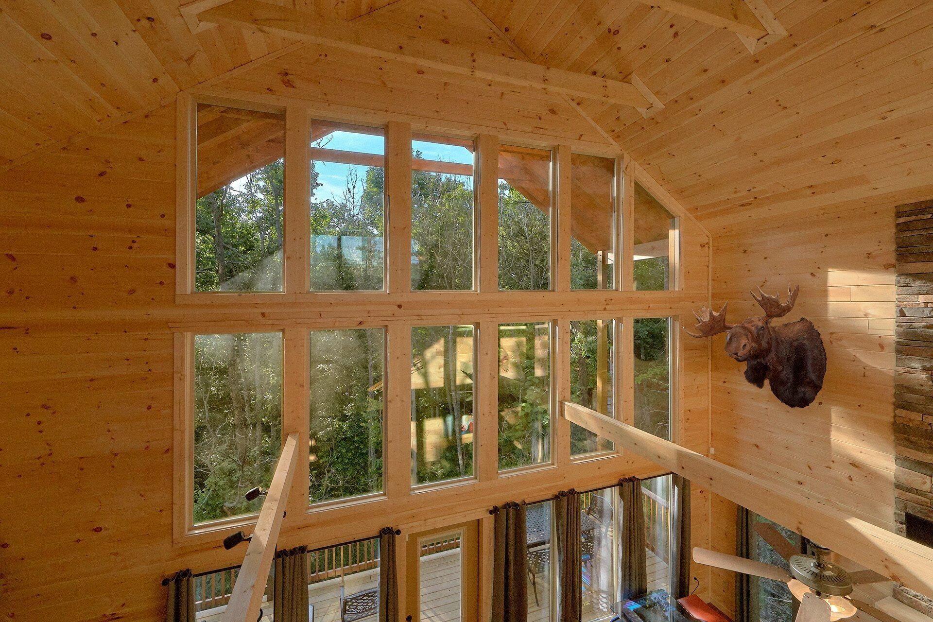 Un intérieur en bois, doté de grandes fenêtres, d’un escalier et d’une tête d’animal fixée au mur.