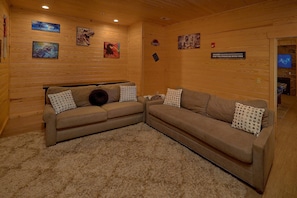 Ein gemütliches Zimmer mit Holzvertäfelung, einer Eckcouch und Wandbildern zum Thema Dinosaurier.
