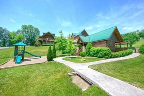 A lodge with a playground, a covered walkway, and a well-maintained lawn. - Poolside Lodge Cabin Rental (Sevierville)
