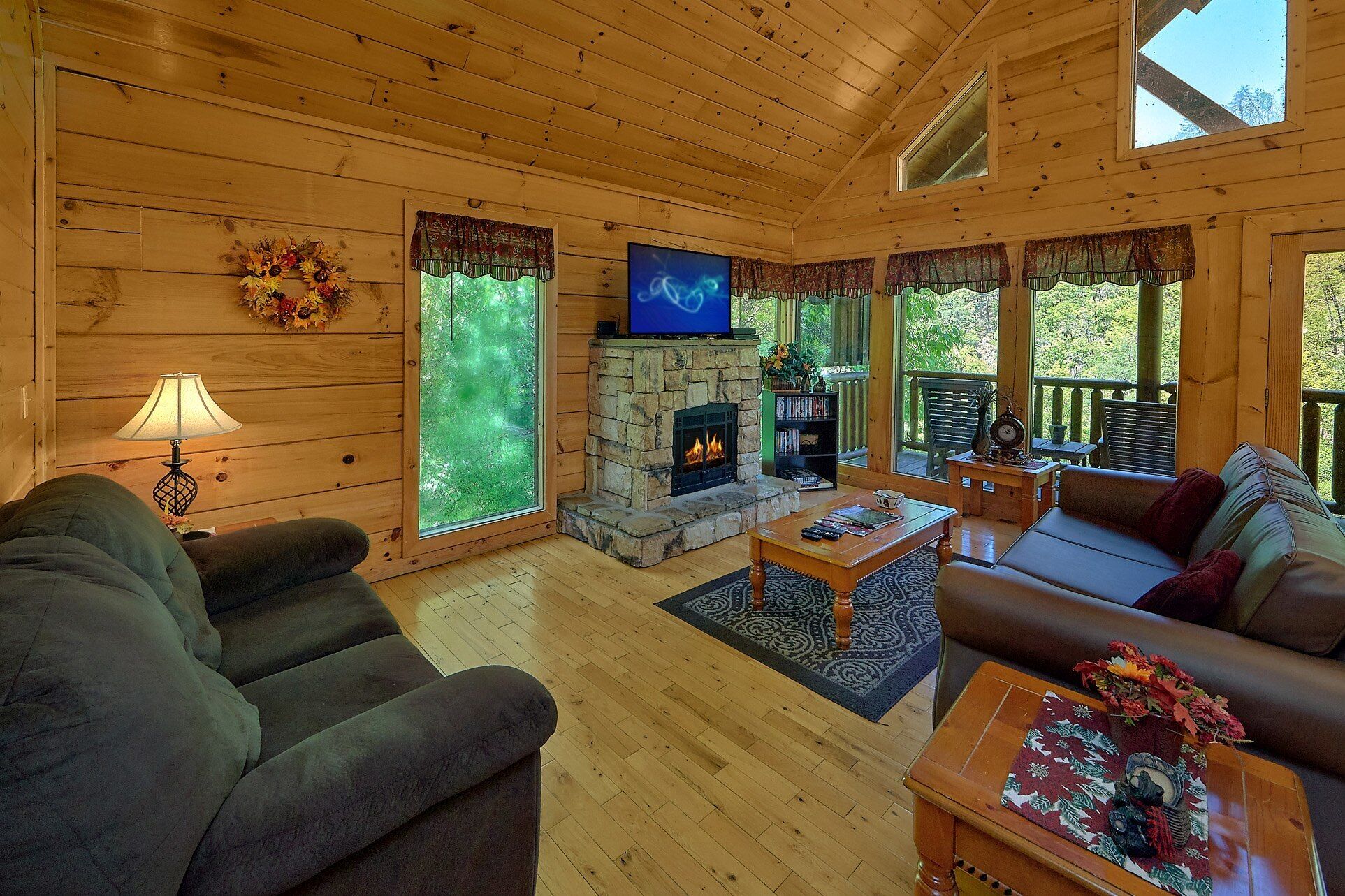 A cozy cabin interior with a stone fireplace, wooden walls, and a comfortable seating area.
