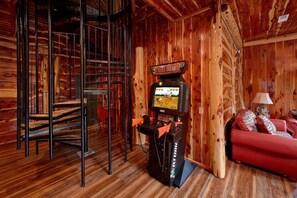 Ein Holzinnenraum mit einer Spielkonsole, einer Treppe und einem roten Sofa.