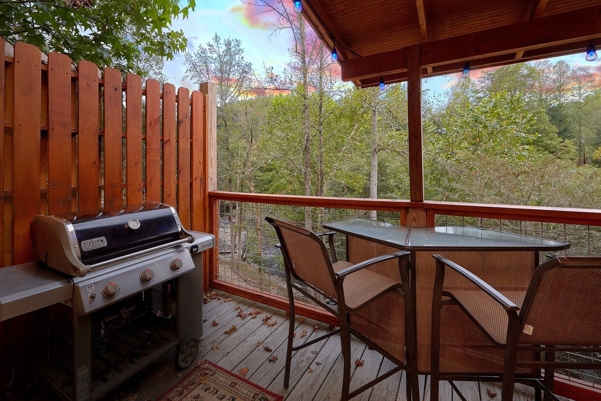 Une terrasse en bois avec un barbecue, une table et des chaises.