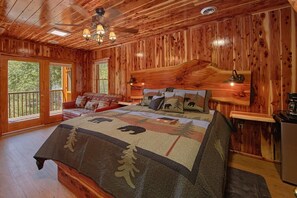 A log cabin bedroom with a large bed, a sofa, and a desk. - River Pleasures | Hot Tub, Game Room, Sleeps 10, Fire Pit, Pet Friendly + Free Attraction Tickets (Sevierville)