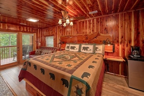 Ein Schlafzimmer in einer Holzhütte mit einem Bett, einem Nachttisch, einer Lampe und einem Fenster.