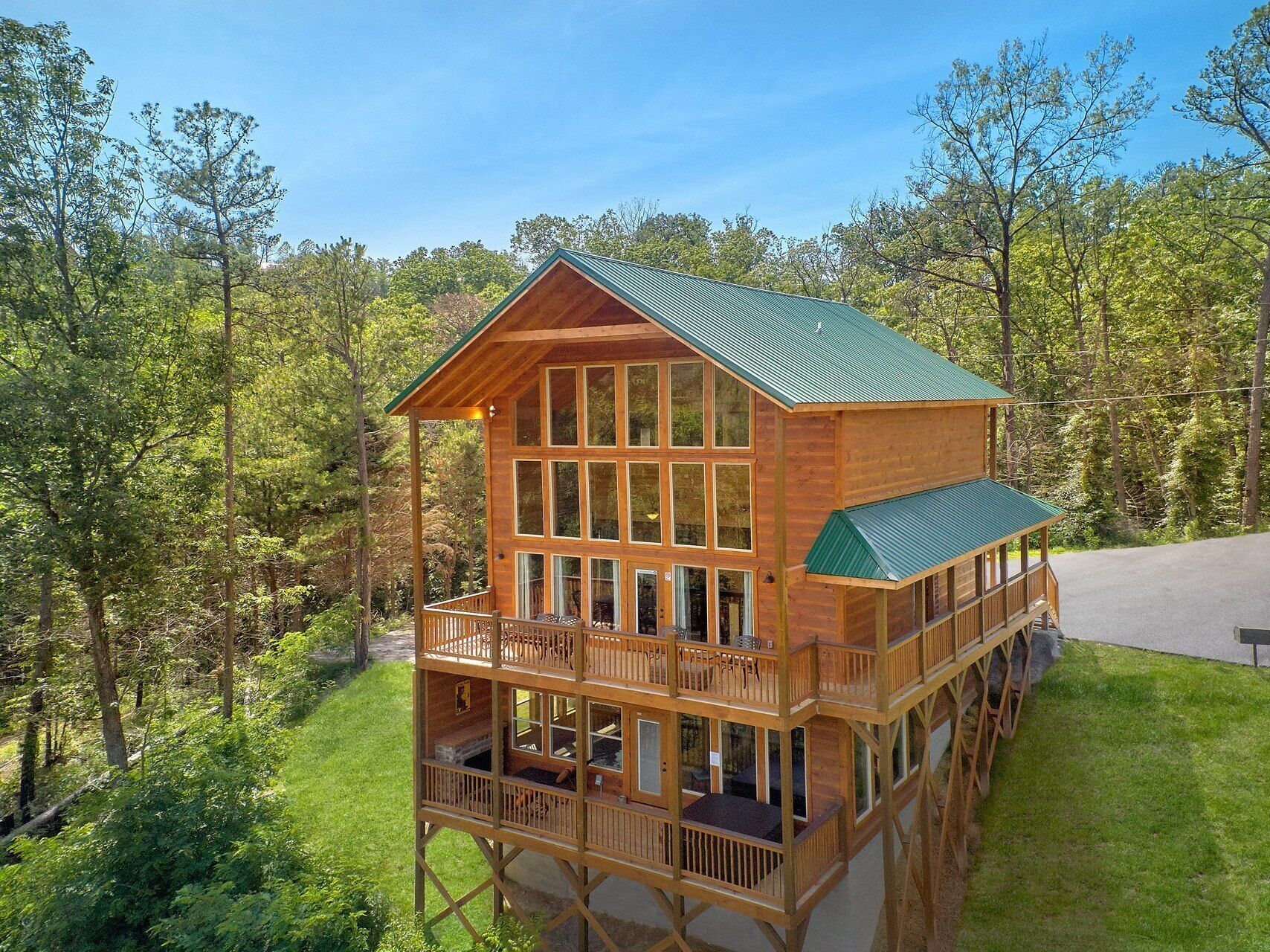 A two-story wooden cabin with a balcony, surrounded by trees.