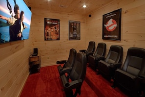 A movie theater with a red carpet, wooden walls, and posters for 'Ocean's Eleven' and 'Ghostbusters'. - Scenic Mountain Pool | Private Pool, Hot Tub, Near Dollywood, Game Room + Free Attraction Tickets (Pigeon Forge)