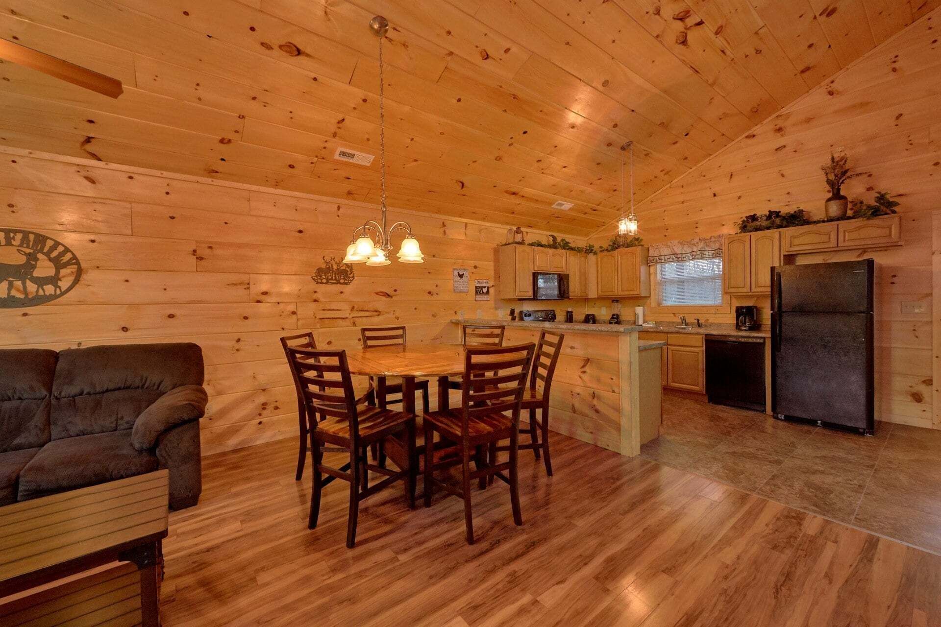 Interior de una cabaña con comedor, cocina y sofá.