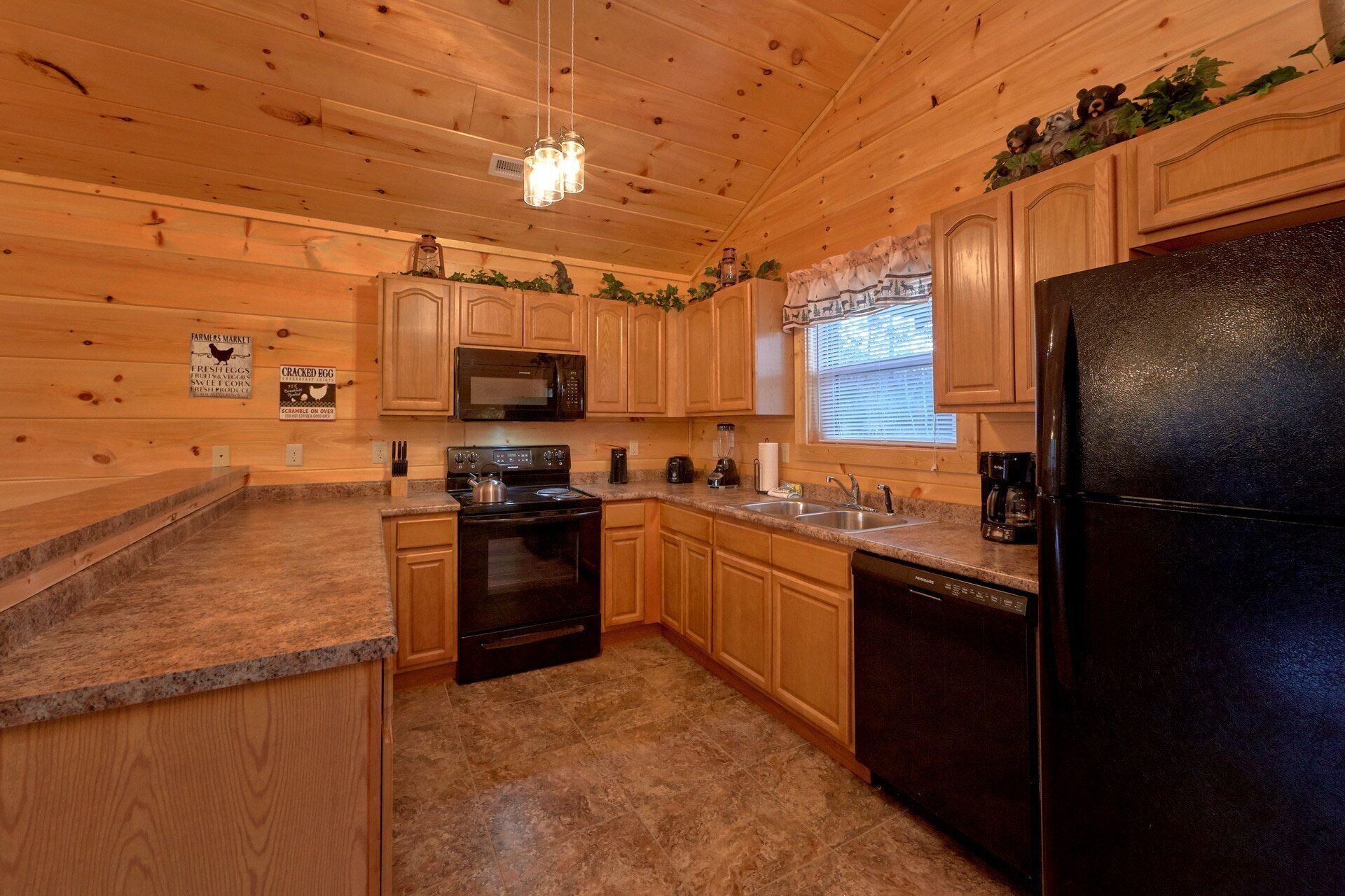 A kitchen with wooden cabinets, a black refrigerator, a microwave, a stove, and a sink.