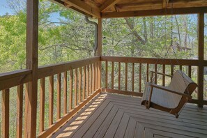 A wooden deck with a swing chair, surrounded by trees. - Serenity Ridge | Mtn Views, Hot Tub, Near Dollywood, Fireplace + Free Attraction Tickets (Pigeon Forge)