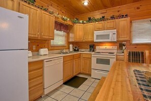Una cocina con armarios de madera, un refrigerador blanco, un microondas, una estufa y un lavavajillas.