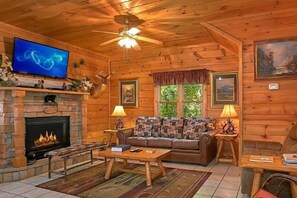 A cozy living room with a fireplace, a sofa, a coffee table, and a television. - Simply Irresistible | Theater, Hot Tub, Game Room, Pigeon Forge, Fireplace + Free Attraction Tickets (Pigeon Forge)