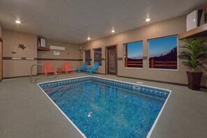 An indoor swimming pool with clear blue water, surrounded by walls with windows, and a few chairs. - Smoky Bear Lodge | Private Pool, Mtn Views, Hot Tub, Game Room, Sleeps 10 + Free Attraction Tickets (Wears Valley)