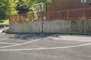 A basketball court with a wooden fence and a stone wall. - Smoky Bear Lodge | Private Pool, Mtn Views, Hot Tub, Game Room, Sleeps 10 + Free Attraction Tickets (Wears Valley)