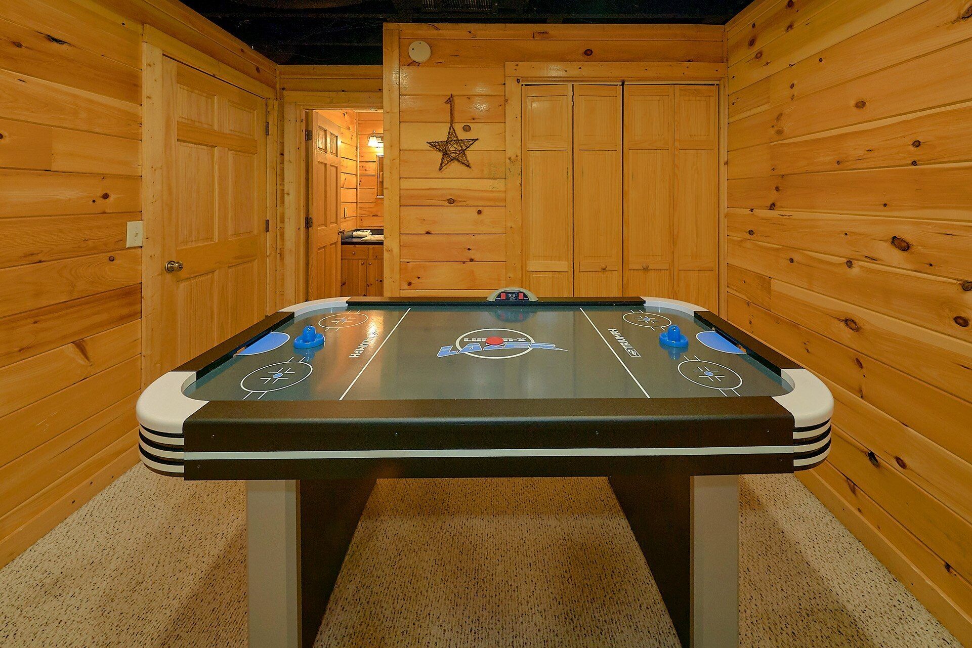 A pool table in a wooden room with a star decoration on the wall.