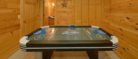 A pool table in a wooden room with a star decoration on the wall.