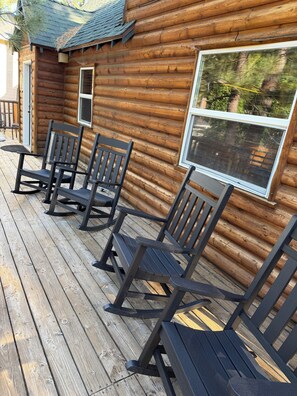 Eine Blockhütte mit Veranda und vier Schaukelstühlen.