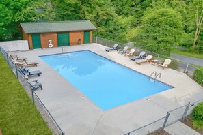 A rectangular swimming pool with a wooden deck, surrounded by lounge chairs and a small building with a green door. - Smoky Mountain Lodge | Sleeps 17, Theater, Hot Tub, Game Room, King Suites + Free Attraction Tickets (Pigeon Forge)