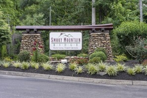 A sign for Smoky Mountain Ridge with a rustic design, surrounded by landscaped greenery. - Splashin On Majestic Mountain | Private Pool, Theater, Smoky Mtn Views + Free Attraction Tickets (Sevierville)