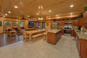 A spacious kitchen with wooden cabinets, a large island, and modern appliances. - Splashin On Majestic Mountain | Private Pool, Theater, Smoky Mtn Views + Free Attraction Tickets (Sevierville)