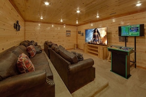 A cozy room with a leather sofa, a large TV screen, and a video game console. - Splashin On Majestic Mountain | Private Pool, Theater, Smoky Mtn Views + Free Attraction Tickets (Sevierville)