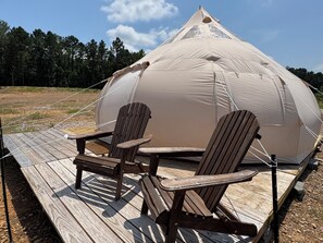 A dome-shaped tent with two wooden chairs on a wooden deck.