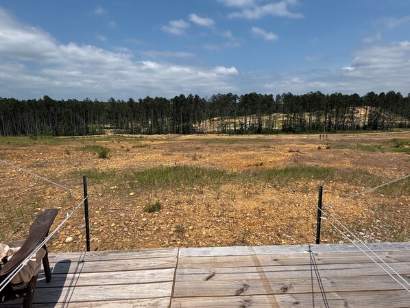 Terraza de madera con vista a un área boscosa y cielo despejado.