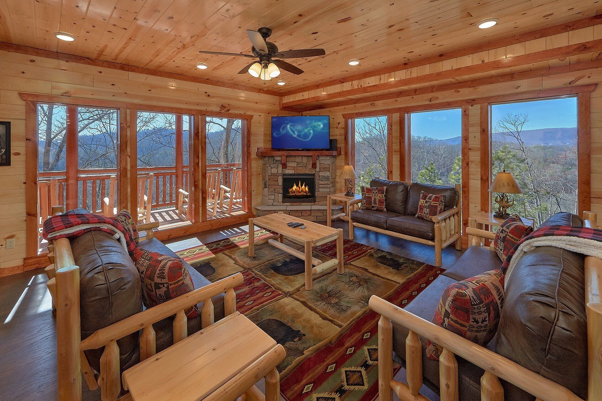 A cozy cabin interior with a fireplace, wooden furniture, and large windows offering a mountain view.