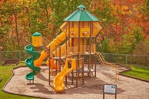 A playground with multiple slides and a climbing structure. - Sugar and Spice | Mtn Views, Hot Tub, Game Room, Sleeps 10, King Suites + Free Attraction Tickets (Sevierville)