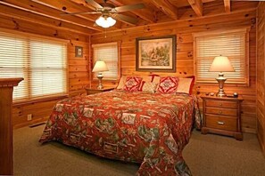 A wooden cabin bedroom with a bed, two nightstands, and a ceiling fan. - Sugar and Spice | Mtn Views, Hot Tub, Game Room, Sleeps 10, King Suites + Free Attraction Tickets (Sevierville)