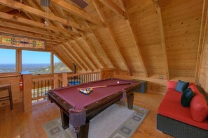 A wooden interior with a pool table, a sofa, and a view through a window. - The Overlook | Smoky Mtn Views, Hot Tub, Near Dollywood, Game Room + Free Attraction Tickets (Pigeon Forge)