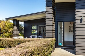 A modern building with a covered outdoor seating area and a clear entrance. - Riverside Retreat (Taupo)