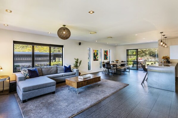 A modern living room with a sofa, coffee table, and artwork on the wall. - Riverside Retreat (Taupo)