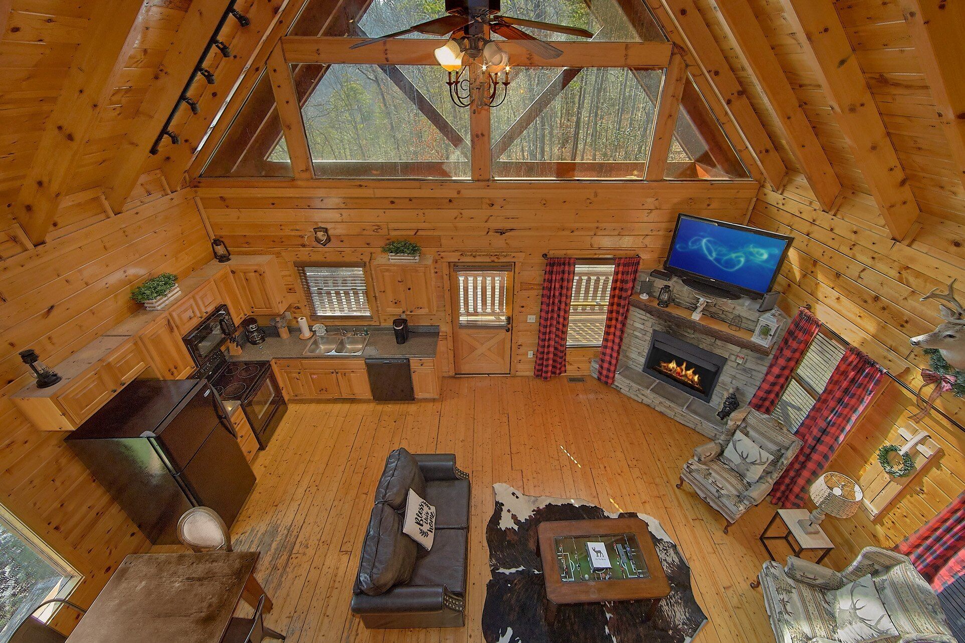 Ein rustikales Holzhaus-Interieur mit Küche, Wohnbereich, Kamin und Fernseher.