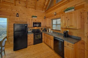 Eine Holzhütte mit einer Küche, inklusive Kühlschrank, Herd, Mikrowelle und Spüle.
