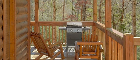 Eine Holzterrasse mit Grill und zwei Schaukelstühlen.