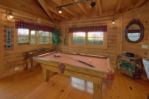 A wooden interior with a pool table, windows with plaid curtains, and a mirror on the wall. - A Romantic Hilltop | Hot Tub | Pool Table (Sevierville)