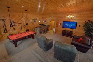 A wooden interior with a pool table, a television, and a dining area. - Mountain Retreat Cabin Rental (Wears Valley)