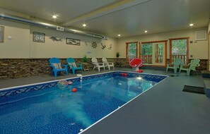 An indoor swimming pool with lounge chairs, a clock, and decorative wall art. - The Big Lebowski | Sleeps 46, Indoor Pool, Theater, Hot Tub, Arcade + Free Attraction Tickets (Pigeon Forge)