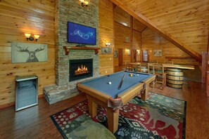 A cozy indoor pool table area with a fireplace, wooden walls, and a television. - The Big Lebowski | Sleeps 46, Indoor Pool, Theater, Hot Tub, Arcade + Free Attraction Tickets (Pigeon Forge)