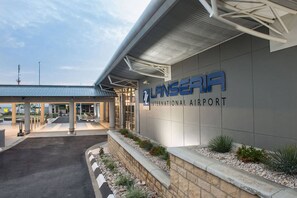 An airport terminal with a clear entrance, a sign reading 'LANSERIA INTERNATIONAL AIRPORT', and a covered walkway. - Experience Elevated Living in Dainfern's Panorama Suite (Johannesburg)